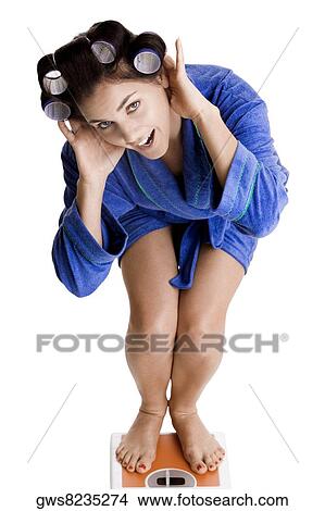 Portrait of a young woman with curlers in her hair standing on a weight scale View Large Photo Image Picture - Portrait of a young woman with curlers in her hair standing on a weight scale. Fotosearch