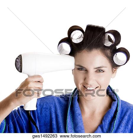 Portrait of a young woman with curlers in her hair holding a hairdryer View Large Photo Image Stock Image - Portrait of a young woman with curlers in her hair holding a hairdryer. Fotosearch