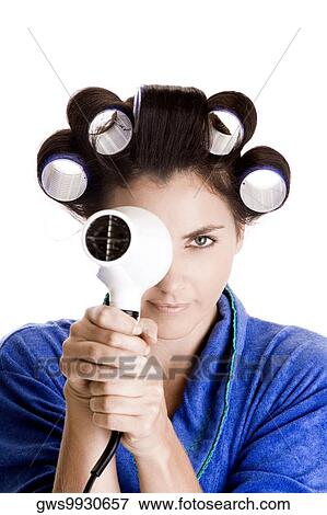 Portrait of a young woman with curlers in her hair holding a hairdryer View Large Photo Image Stock Photo - Portrait of a young woman with curlers in her hair holding a hairdryer. Fotosearch