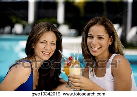 Stock Photo - Portrait of two young women holding juice glasses. Fotosearch