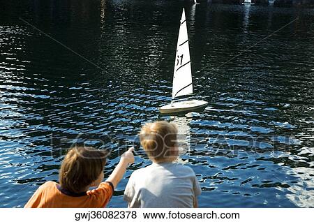 Rear view of a boy and a girl sitting beside a lake, New York City, New York State, USA View Large Photo Image Stock Photo - Rear view of a boy and a girl sitting beside a lake, New York City, New York State, USA. Fotosearch