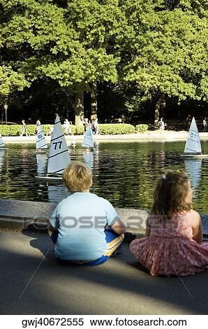 Rear view of a boy and a girl sitting beside a lake, New York City, New York State, USA View Large Photo Image Stock Photography - Rear view of a boy and a girl sitting beside a lake, New York City, New York State, USA. Fotosearch