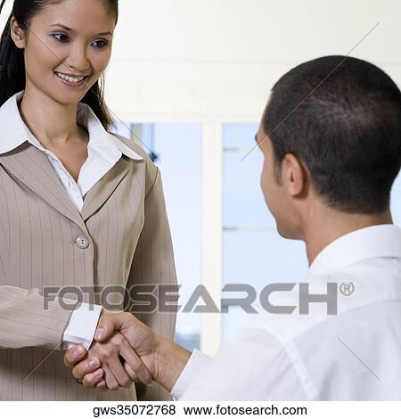 Rear view of a businessman shaking hands with a businesswoman View Large Photo Image Stock Photo - Rear view of a businessman shaking hands with a businesswoman. Fotosearch