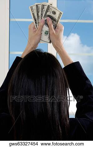Rear view of a businesswoman holding American paper currency View Large Photo Image Picture - Rear view of a businesswoman holding American paper currency. Fotosearch