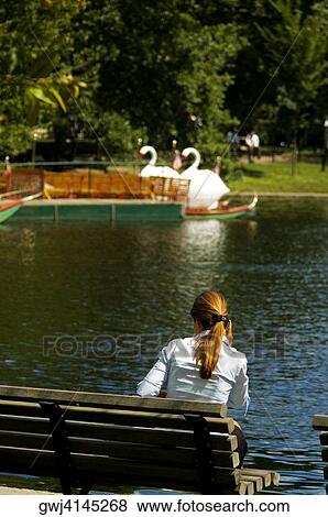 Rear view of a woman sitting on a bench View Large Photo Image Stock Photo - Rear view of a woman sitting on a bench. Fotosearch