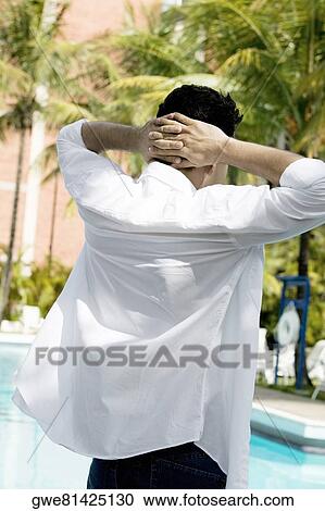Rear view of a young man standing with hands behind his head View Large Photo Image Stock Image - Rear view of a young man standing with hands behind his head. Fotosearch