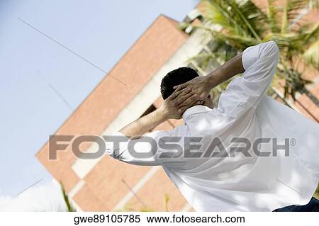 Rear view of a young man standing with hands behind his head View Large Photo Image Stock Photography - Rear view of a young man standing with hands behind his head. Fotosearch