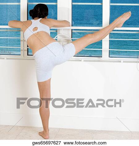 Rear view of a young woman stretching her legs View Large Photo Image Stock Photo - Rear view of a young woman stretching her legs. Fotosearch
