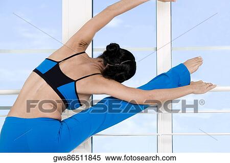 Stock Photography - Rear view of a young woman stretching her legs. Fotosearch