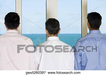 Rear view of three men standing side by side View Large Photo Image Stock Photo - Rear view of three men standing side by side. Fotosearch