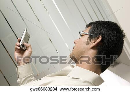 Picture - Side profile of a businessman holding a mobile phone. Fotosearch