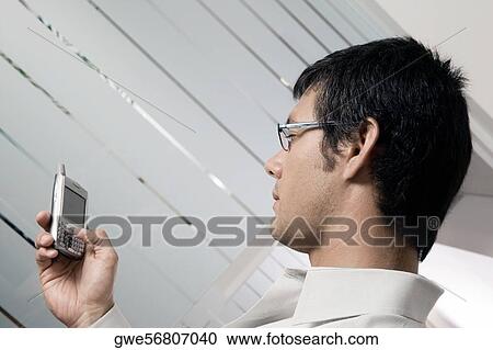 Side profile of a businessman holding a mobile phone View Large Photo Image Stock Image - Side profile of a businessman holding a mobile phone. Fotosearch