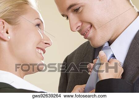 Side profile of a businesswoman adjusting a businessman's tie View Large Photo Image Picture - Side profile of a businesswoman adjusting a businessman's tie. Fotosearch