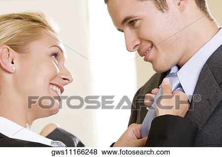 Side profile of a businesswoman adjusting a businessman's tie View Large Photo Image Stock Photo - Side profile of a businesswoman adjusting a businessman's tie. Fotosearch
