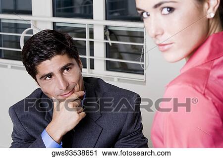 Stock Image - Side profile of a businesswoman with a businessman looking at her. Fotosearch
