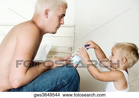 Side profile of a father and his son holding a bottle View Large Photo Image Picture - Side profile of a father and his son holding a bottle. Fotosearch