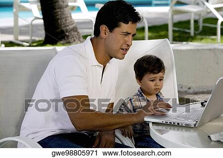 Side profile of a father working on a laptop with his son View Large Photo Image Stock Image - Side profile of a father working on a laptop with his son. Fotosearch