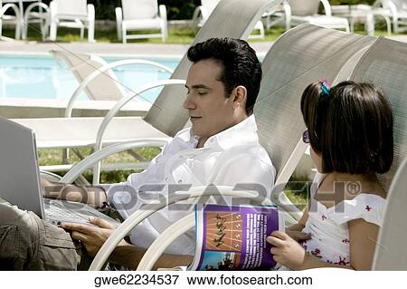Side profile of a father working on a laptop with his daughter sitting beside him View Large Photo Image Stock Photo - Side profile of a father working on a laptop with his daughter sitting beside him. Fotosearch