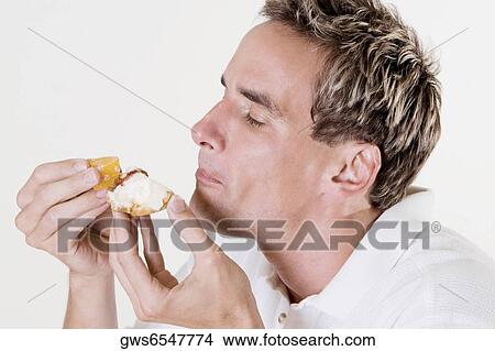 Side profile of a mid adult man eating a fruit tart View Large Photo Image Picture - Side profile of a mid adult man eating a fruit tart. Fotosearch