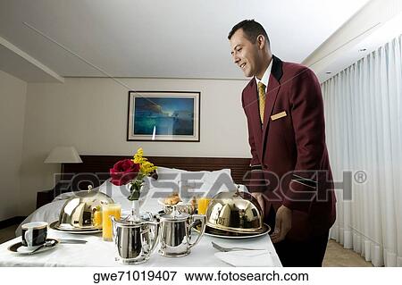 Side profile of a waiter serving food View Large Photo Image Stock Photo - Side profile of a waiter serving food. Fotosearch