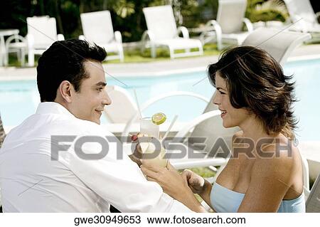 Stock Image - Side profile of a young couple holding drinks. Fotosearch