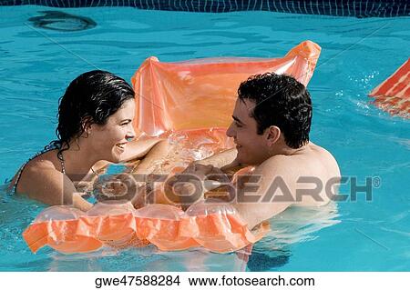 Picture - Side profile of a young couple in a swimming pool. Fotosearch