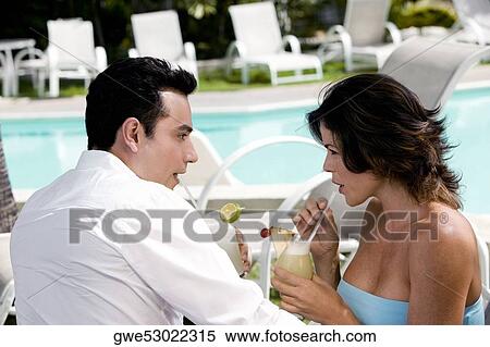 Stock Photography - Side profile of a young couple sipping drinks. Fotosearch