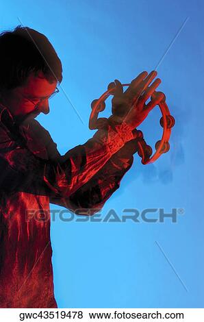 Side profile of a young man playing the tambourine View Large Photo Image Stock Photo - Side profile of a young man playing the tambourine. Fotosearch