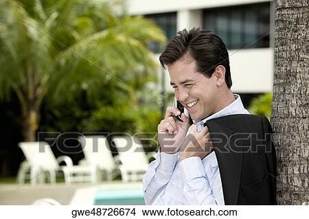 Picture - Side profile of a young man talking on a mobile phone. Fotosearch