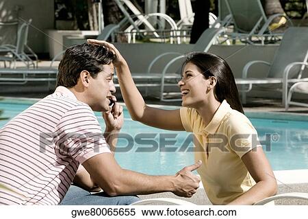 Side profile of a young man talking on a mobile phone with a young woman sitting in front of him View Large Photo Image Stock Photography - Side profile of a young man talking on a mobile phone with a young woman sitting in front of him. Fotosearch