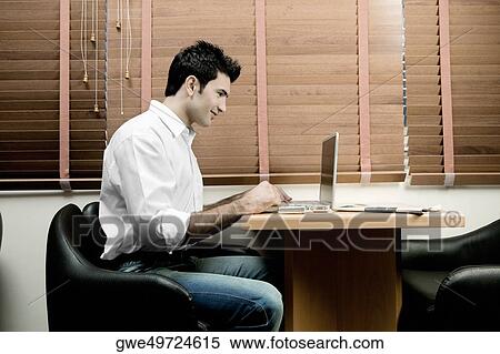 Side profile of a young man using a laptop View Large Photo Image Stock Photography - Side profile of a young man using a laptop. Fotosearch