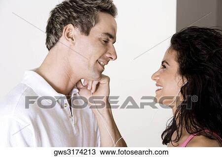 Side profile of a young woman and a mid adult man listening to music through earphones View Large Photo Image Stock Image - Side profile of a young woman and a mid adult man listening to music through earphones. Fotosearch