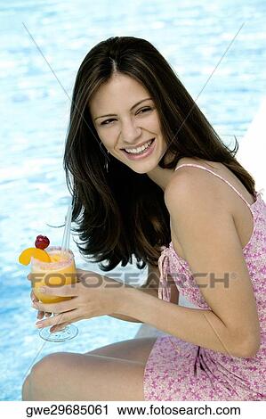 Side profile of a young woman holding a glass of juice View Large Photo Image Stock Image - Side profile of a young woman holding a glass of juice. Fotosearch