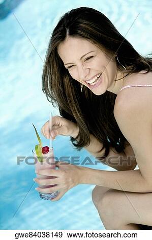 Stock Photo - Side profile of a young woman holding a glass of juice. Fotosearch