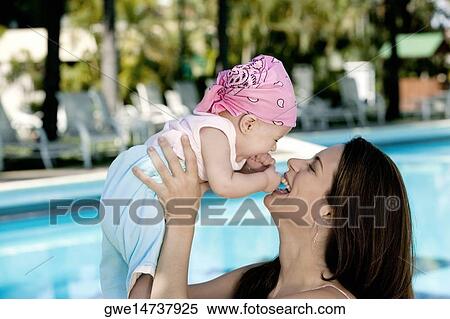 Side profile of a young woman picking up her daughter View Large Photo Image Stock Photography - Side profile of a young woman picking up her daughter. Fotosearch