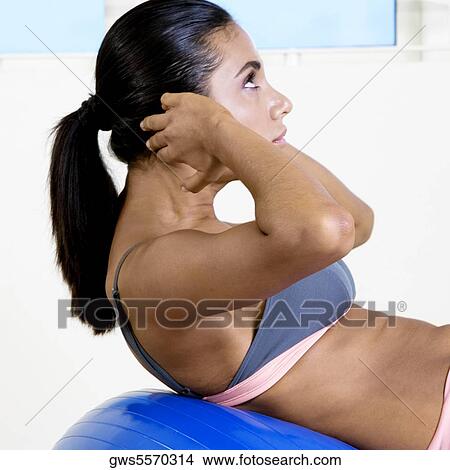 Side profile of a young woman exercising with a fitness ball View Large Photo Image Picture - Side profile of a young woman exercising with a fitness ball. Fotosearch