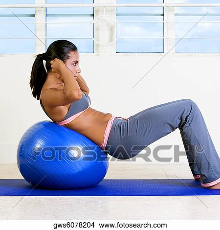 Side profile of a young woman exercising with a fitness ball View Large Photo Image Picture - Side profile of a young woman exercising with a fitness ball. Fotosearch