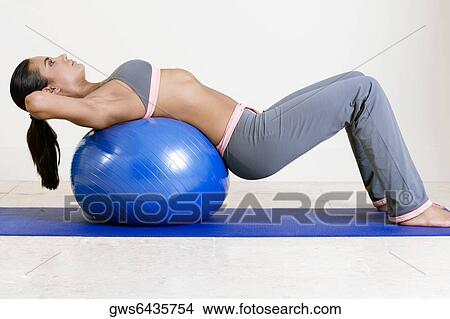 Side profile of a young woman exercising with a fitness ball View Large Photo Image Picture - Side profile of a young woman exercising with a fitness ball. Fotosearch