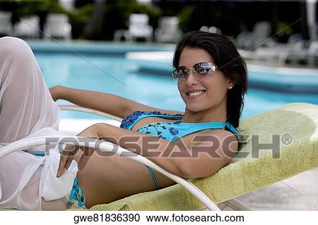Stock Image - Side profile of a young woman resting on a lounge chair. Fotosearch