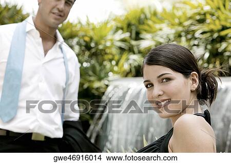Picture - Side profile of a young woman smiling with a young man standing in front of her. Fotosearch