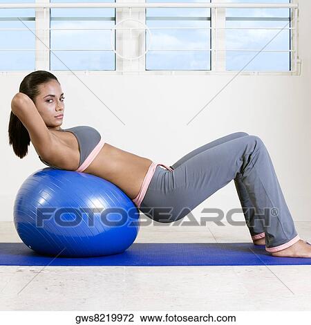 Side profile of a young woman exercising with a fitness ball View Large Photo Image Stock Image - Side profile of a young woman exercising with a fitness ball. Fotosearch