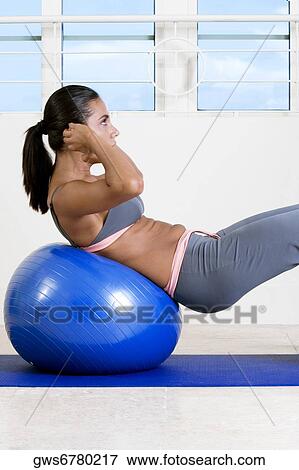 Side profile of a young woman exercising with a fitness ball View Large Photo Image Stock Photo - Side profile of a young woman exercising with a fitness ball. Fotosearch