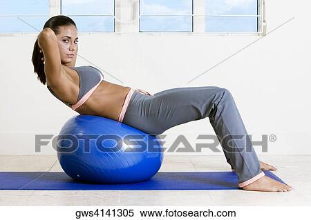 Side profile of a young woman exercising with a fitness ball View Large Photo Image Stock Photography - Side profile of a young woman exercising with a fitness ball. Fotosearch