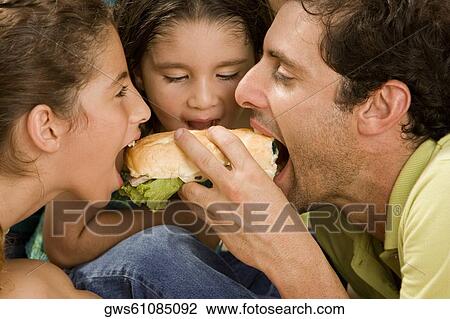 Side profile of parents and their daughter eating a burger View Large Photo Image Stock Image - Side profile of parents and their daughter eating a burger. Fotosearch