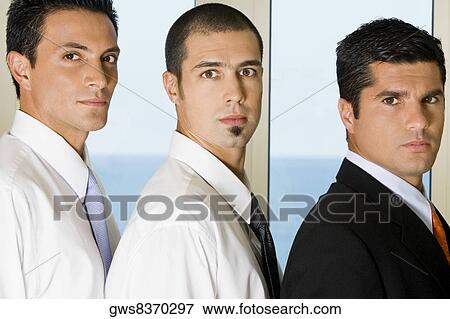 Stock Photo - Side profile of three businessmen standing in a row. Fotosearch