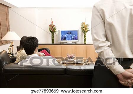 Three people watching television View Large Photo Image Stock Photo - Three people watching television. Fotosearch