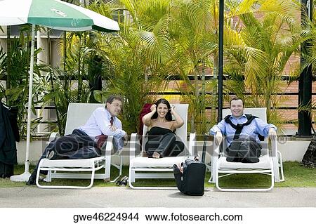 Two businessmen and a businesswoman sitting on lounge chairs View Large Photo Image Picture - Two businessmen and a businesswoman sitting on lounge chairs. Fotosearch
