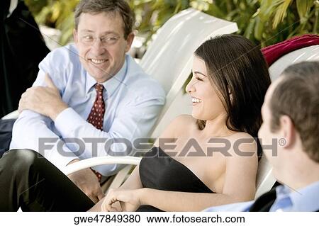 Two businessmen and a businesswoman sitting on lounge chairs View Large Photo Image Stock Image - Two businessmen and a businesswoman sitting on lounge chairs. Fotosearch