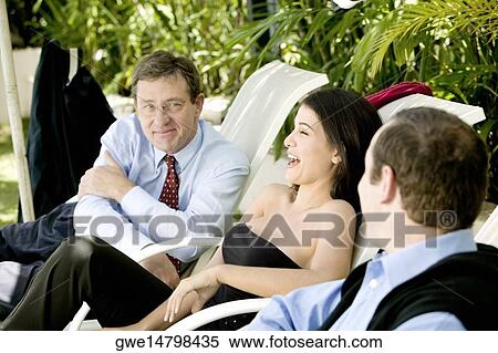 Two businessmen and a businesswoman sitting on lounge chairs View Large Photo Image Stock Photography - Two businessmen and a businesswoman sitting on lounge chairs. Fotosearch