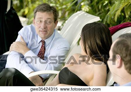 Two businessmen and a businesswoman talking View Large Photo Image Stock Photography - Two businessmen and a businesswoman talking. Fotosearch